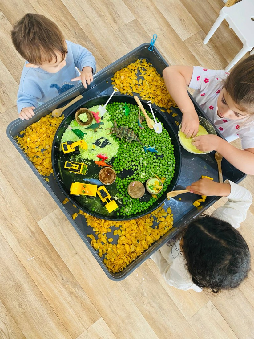 Children playing with dinosaurs and diggers in a sensory tray