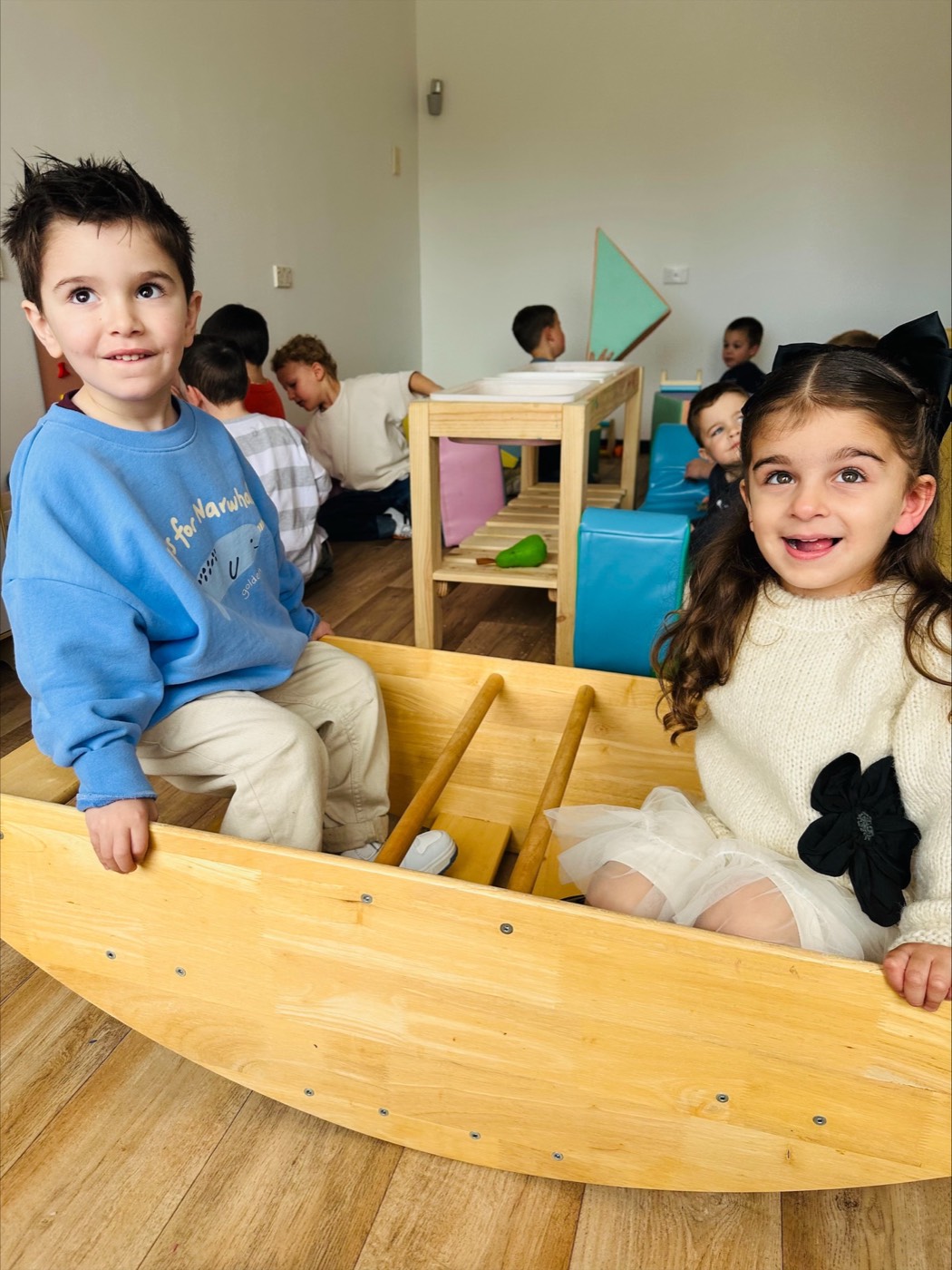 Two children smiling on the wooden rocker