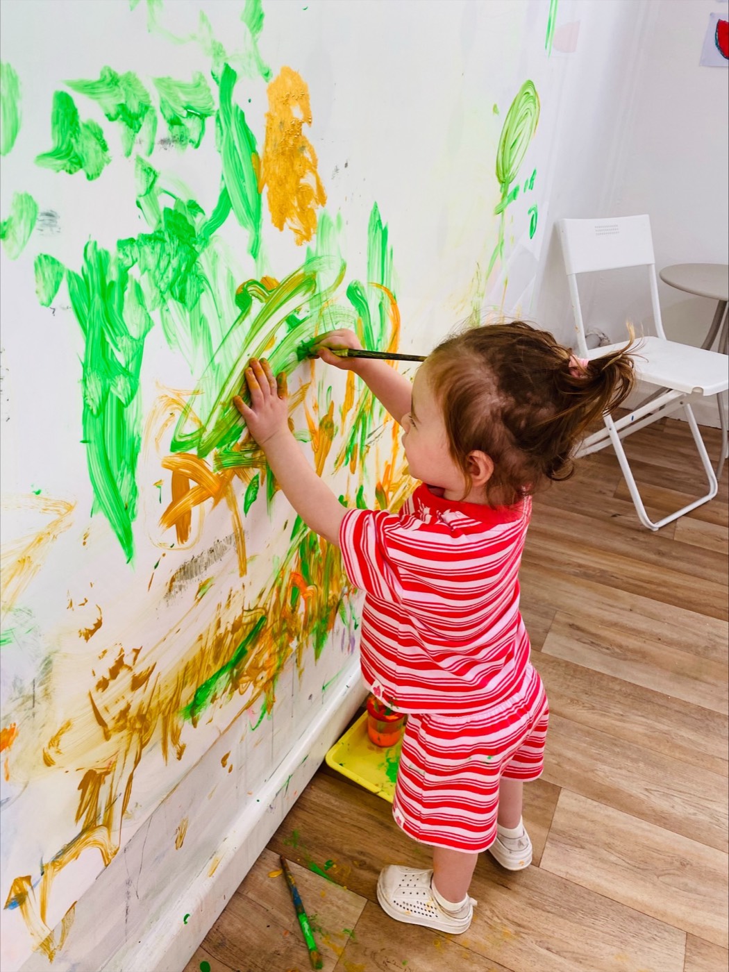 Toddler painting the messy play wall at a play session
